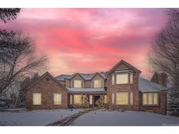 Brick two-story house with a three-car garage, nestled on a snow-covered lot at 4681 S Columbine Ct, Cherry Hills Village, CO 80113
