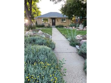 Charming brick home featuring professional landscaping, green lawn, and a paved walkway leading to the front door at 3341 Oneida St, Denver, CO 80207