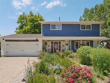 Charming two-story home with a blue exterior, beautiful landscaping and a red front door at 9325 Utica St, Westminster, CO 80031