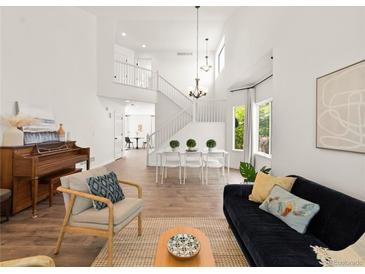 Bright, open living room with hardwood floors, modern furnishings, and large windows providing ample natural light at 11842 Altura St, Commerce City, CO 80603