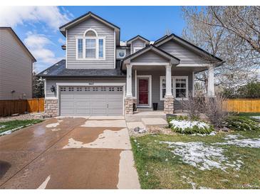 Charming two-story home featuring a covered front porch, well-maintained lawn, and attached two car garage at 9407 W Gibraltar Pl, Littleton, CO 80127