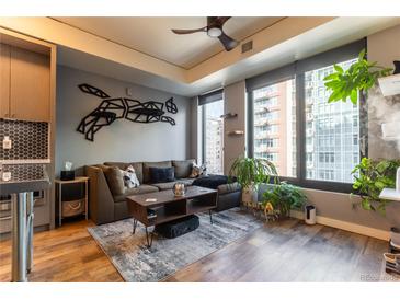 Bright living room featuring a comfortable couch, hardwood floors and modern decor and large windows with city views at 1750 Wewatta St # 705, Denver, CO 80202