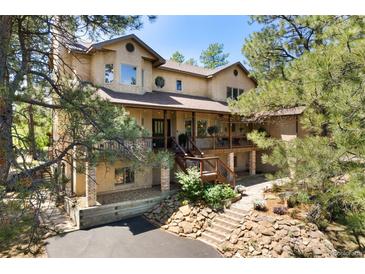 Charming two-story home with a covered porch and mature trees around the front yard at 17015 Oxbridge Rd, Monument, CO 80132