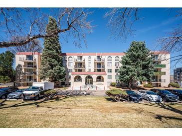 Apartment complex with red roof, beige exterior, manicured landscaping, and ample parking for residents and guests at 7801 W 35Th Ave # 405, Wheat Ridge, CO 80033