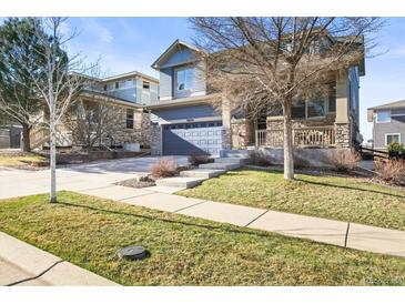 Charming two-story home featuring a stone-accented facade, covered porch and well-maintained lawn in a friendly neighborhood at 26890 E Roxbury Pl, Aurora, CO 80016