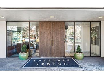 Building entrance with double doors, glass sidelights, planters, and doormat that reads, 