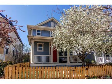 Charming two-story home with a red door, inviting front porch, well-manicured lawn, and beautiful flowering tree at 3353 Wabash St, Denver, CO 80238