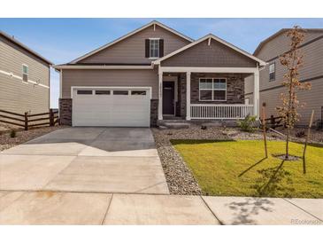 Charming home featuring a covered porch, stone accents, a well-kept lawn, and a two-car garage at 27694 E Byers Ave, Aurora, CO 80018