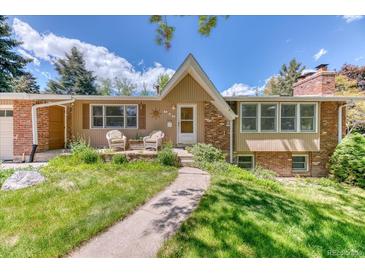 Charming brick home with a manicured lawn and inviting front porch with chairs at 879 S Cole Dr, Lakewood, CO 80228