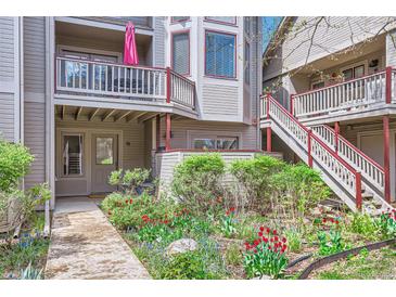 Charming condo exterior with colorful flowers, gray siding, and red trim accents on the staircase and second story balcony at 275 Pearl St # 11, Boulder, CO 80302