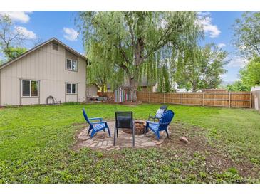 Spacious backyard featuring a fire pit with chairs and a large, mature tree providing ample shade at 32 Powder Horn Pl, Longmont, CO 80504