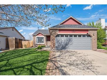 Charming brick-and-red-sided home with a well-maintained lawn, mature tree, and attached two-car garage at 7598 Jared Way, Littleton, CO 80125