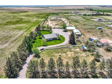 Aerial view of a sprawling farm with a well-maintained home, outbuildings, and fenced pastures, perfect for rural living at 50950 E 32Nd Ave, Bennett, CO 80102