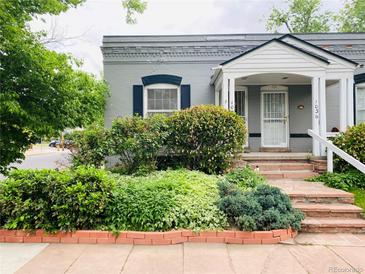 Charming gray home featuring lovely landscaping and a welcoming covered front porch at 1038 E 4Th Ave, Denver, CO 80218