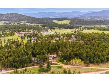 Expansive aerial view of a private home nestled in a lush forest with mountains in the distance at 25808 Sunrise Ln, Golden, CO 80401