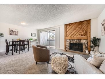 Cozy living room features a stone fireplace, balcony access, and comfortable seating arrangement at 14066 E Stanford Cir # H08, Aurora, CO 80015