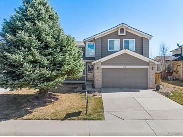 Charming two-story home features a well-manicured front yard with mature tree, and attached two-car garage at 6725 Lionshead Pkwy, Lone Tree, CO 80124