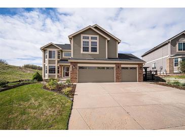 Charming two-story home with a three-car garage and well-manicured lawn and blue sky at 1076 Switch Grass Dr, Castle Rock, CO 80109