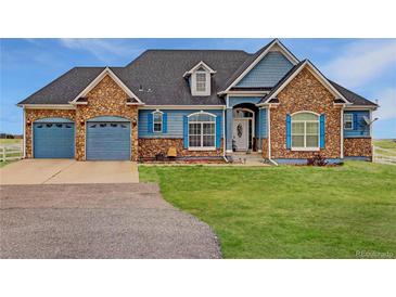 Charming home with stone accents, blue siding, and a well-manicured lawn on a sunny day at 38025 E 145Th Pl, Keenesburg, CO 80643
