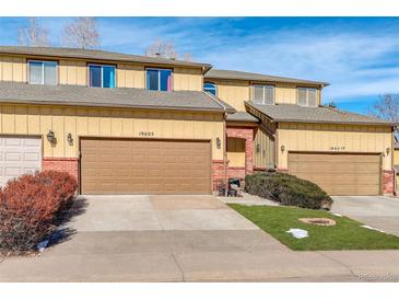 Inviting townhome featuring a two-car garage, a well-kept lawn, and sunny yellow siding at 18605 E Saratoga Pl, Aurora, CO 80015