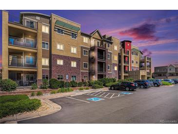 Beautiful apartment building with colorful architectural details and a well-maintained parking lot at dusk at 1044 Rockhurst Dr # 207, Highlands Ranch, CO 80129