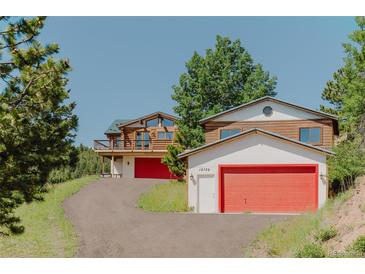 Inviting log cabin exterior with a red garage door and a charming mountain setting at 12135 Cochise Cir, Conifer, CO 80433