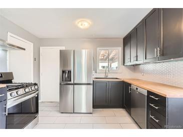 Updated kitchen features stainless steel appliances, new countertops, and stylish backsplash at 755 Newark St, Aurora, CO 80010