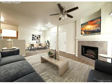 Cozy living room featuring a fireplace, ceiling fan, and view into the dining area at 4451 S Ammons St # 108, Littleton, CO 80123