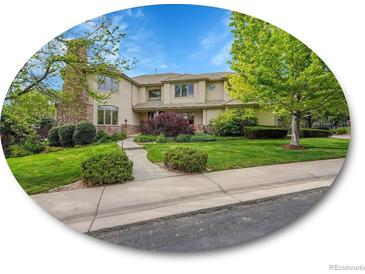 Charming two-story home featuring a stone chimney and beautifully landscaped front yard with mature trees at 291 Fairchild Dr, Highlands Ranch, CO 80126