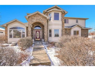 Charming two-story home featuring a stone arched entry, well-maintained landscaping, and a welcoming facade at 6943 Saddleback Ave, Firestone, CO 80504
