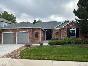 Charming single-story red brick home with a well-manicured lawn and attached two-car garage at 8717 Forrest Dr, Highlands Ranch, CO 80126