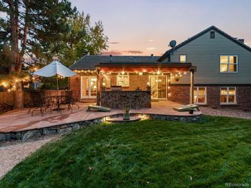 Outdoor entertaining space featuring a built-in grill, stone patio, and lawn at 7668 S Locust St, Centennial, CO 80112