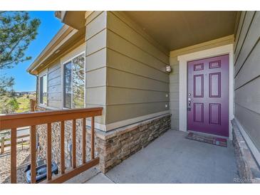 Inviting front porch with a plum colored door and stone accents at 7511 S Sicily Way, Aurora, CO 80016