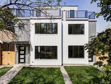 Modern two-story home boasts a rooftop terrace, sleek white facade, and manicured front lawn at 1541 Glencoe St, Denver, CO 80220