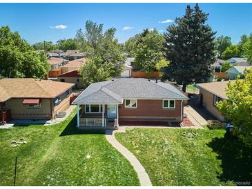 Charming brick home featuring a well-maintained lawn, a covered porch and mature trees in a peaceful neighborhood at 1852 S Decatur St, Denver, CO 80219