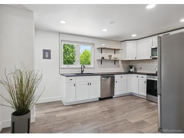 Modern kitchen features white cabinets, stainless steel appliances, and wood-style flooring at 1852 S Decatur St, Denver, CO 80219