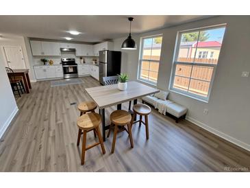 Bright kitchen features white cabinets, stainless steel appliances, and a table with four wood chairs at 9036 Mandel St, Denver, CO 80260