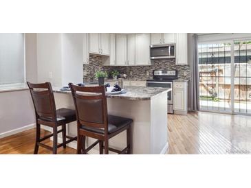 Modern kitchen with white cabinetry, granite countertops, and a breakfast bar, with access to the outdoor patio at 6400 E Mississippi Ave, Denver, CO 80224
