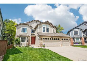 Charming two-story home features a three-car garage, red door, and well-manicured lawn at 775 Poppywood Dr, Highlands Ranch, CO 80126