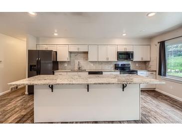 Modern kitchen featuring white cabinets, granite countertops, and stainless steel appliances at 679 S Pearl St, Elizabeth, CO 80107