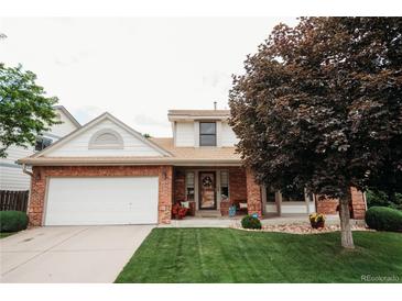 Charming two-story brick home with a well-manicured lawn and inviting front porch at 17530 E Caspian Pl, Aurora, CO 80013