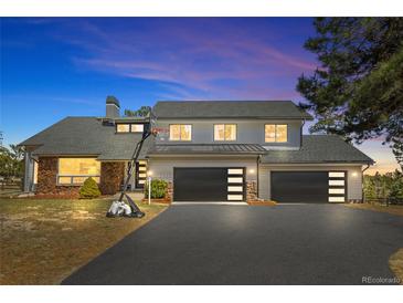 Beautiful two-story home with a well-manicured lawn, dark garage doors, and a basketball hoop out front at 2999 Olympia Cir, Evergreen, CO 80439