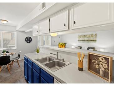 Kitchen area featuring stainless steel sink, blue cabinets, and eat-in dining at 7700 W Glasgow Place # 15A, Littleton, CO 80128