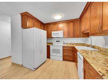 Efficient kitchen with white appliances, wood cabinets, light countertops, and a wood-look floor at 3022 S Wheeling Way # 205, Aurora, CO 80014