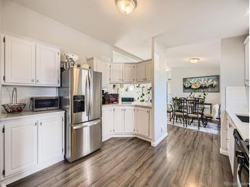 Bright kitchen boasts stainless steel appliances and white cabinetry, flowing into the dining area at 846 S Sheridan Blvd, Denver, CO 80226