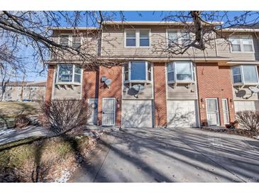 Tan and brick townhouse exterior with attached garage and landscaping at 3300 W Florida Ave # 77, Denver, CO 80219