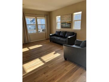 Bright living room with hardwood floors, large windows, and comfortable leather seating at 7414 E 28Th Ave # 4, Denver, CO 80238