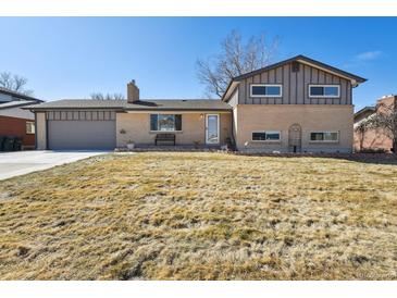 Charming two-story home featuring a manicured lawn and a classic brick facade at 1300 Kennedy Dr, Northglenn, CO 80234