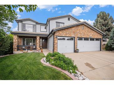 Charming two-story home with a stone facade, well-manicured lawn, and a spacious two-car garage with white doors at 9249 Fox Fire Dr, Highlands Ranch, CO 80129