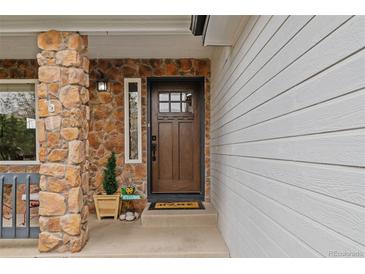 Charming home entrance featuring a beautiful wood door, stone accents, and a welcoming decor at 9249 Fox Fire Dr, Highlands Ranch, CO 80129